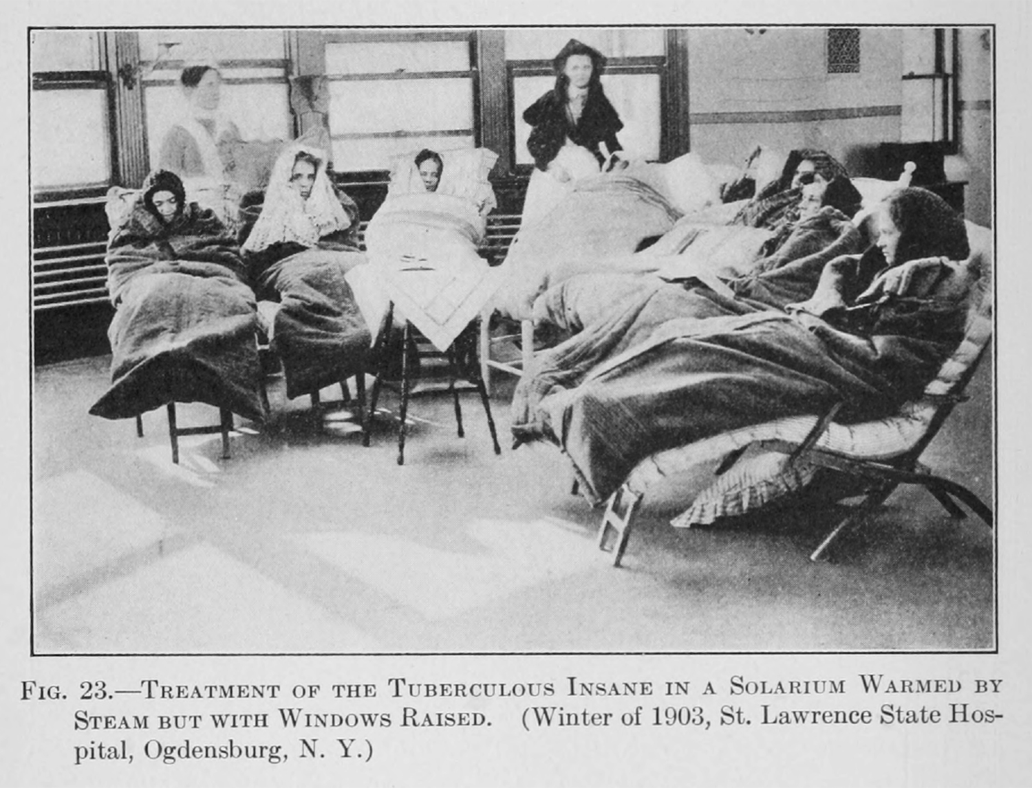 A group of women sit with heavy sleeping bag like blankets around them.